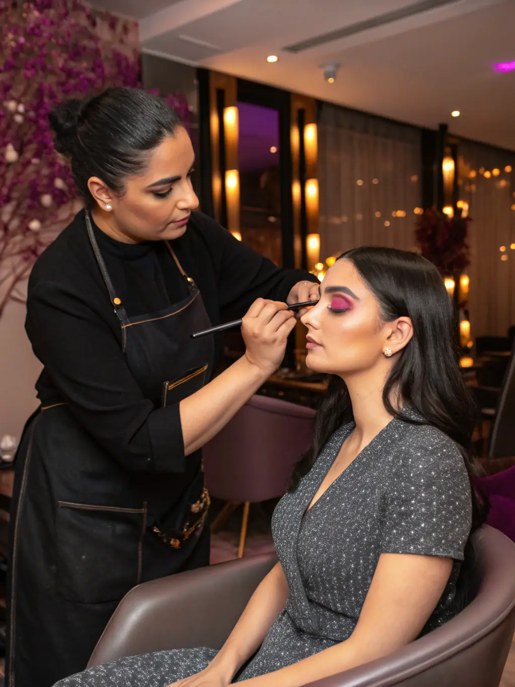Image of a makeup artist carefully applying eyeshadow to a client in a salon chair, showcasing the precision and attention to detail involved in a makeup application.